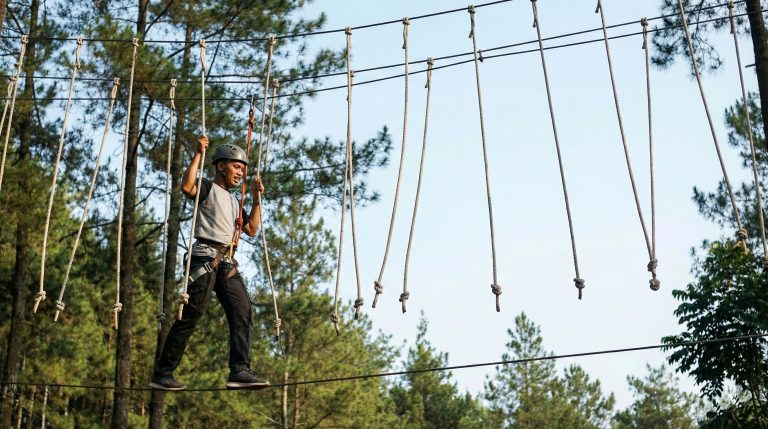 Peserta outbound melangkah di Elvis Walk dengan pijakan tali bergoyang dan tali-tali gantung sebagai pegangan, suasana alam dan peralatan safety lengkap.