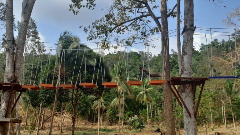 Wahana Jembatan Goyang dengan papan pijakan bergerak kiri-kanan, jembatan outbound di area hutan dengan nuansa petualangan.
